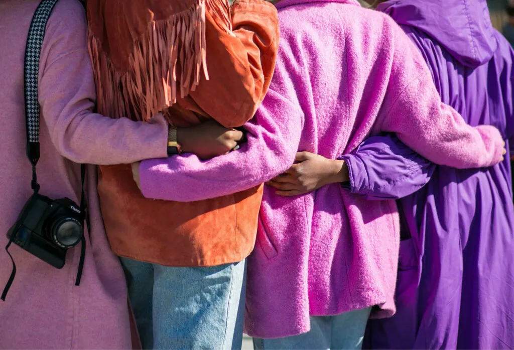 Färgglatt klädda personer står och håller om varandra.
