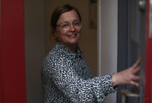Bild på Lotta i dörröppningen till Sociala Missionens öppna mottagning och rådgivning i Stockholm.